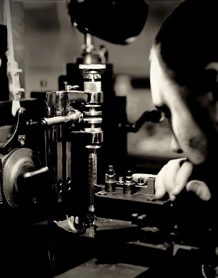 Black and white photo of Chris Manning working on a silver pen at an antique engraving engine.